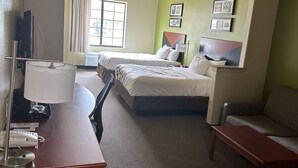 A hotel room with two beds, a desk with a telephone, a chair, and a small table. - Sleep Inn & Suites at Six Flags (San Antonio)