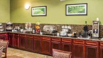 A hotel kitchen with a granite countertop, various appliances, and a seating area with a table and chairs.