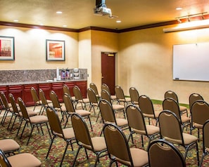 A conference room with rows of chairs, a whiteboard, and a kitchenette area. - Sleep Inn & Suites at Six Flags (San Antonio)