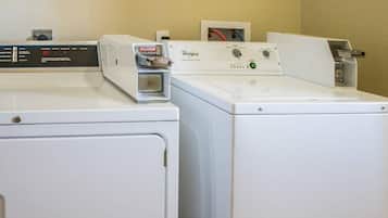 Uma área de lavanderia com duas máquinas de lavar Whirlpool brancas, uma com painel de controle e outra com visor digital.