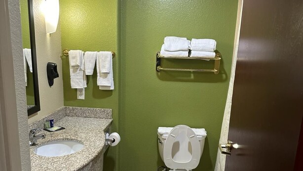 A bathroom with a granite countertop sink, a toilet, and a towel rack. - Sleep Inn & Suites at Six Flags (San Antonio)