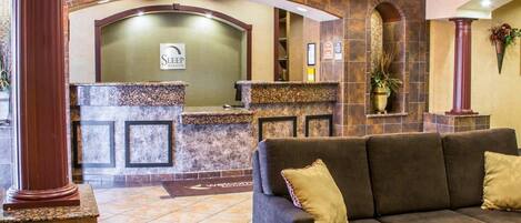 A reception area with a reception desk, a sofa, and a chandelier.