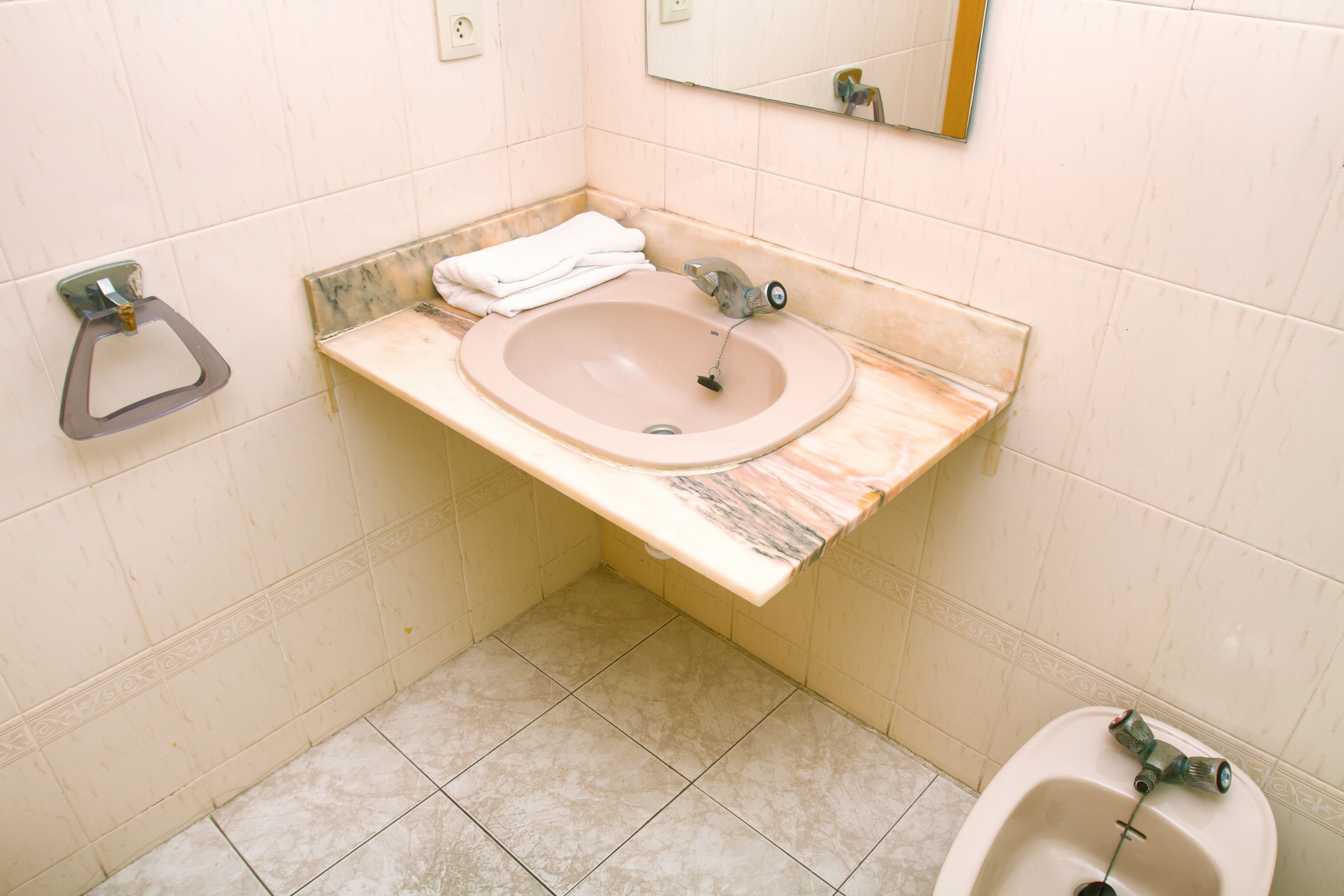 A bathroom with a marble sink, a toilet, and a mirror.