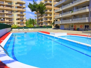 Une piscine bordée de carreaux rouges et blancs, entourée d’un petit muret et agrémentée de quelques chaises longues.