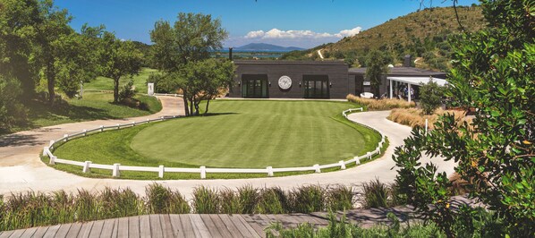 Un campo de golf con un club de campo, una valla blanca y una vista despejada del paisaje circundante.