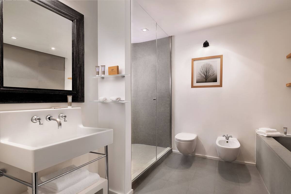 Een moderne badkamer met een wit wastafelmeubel, een douchecabine van glas, een toilet en een bidet.
