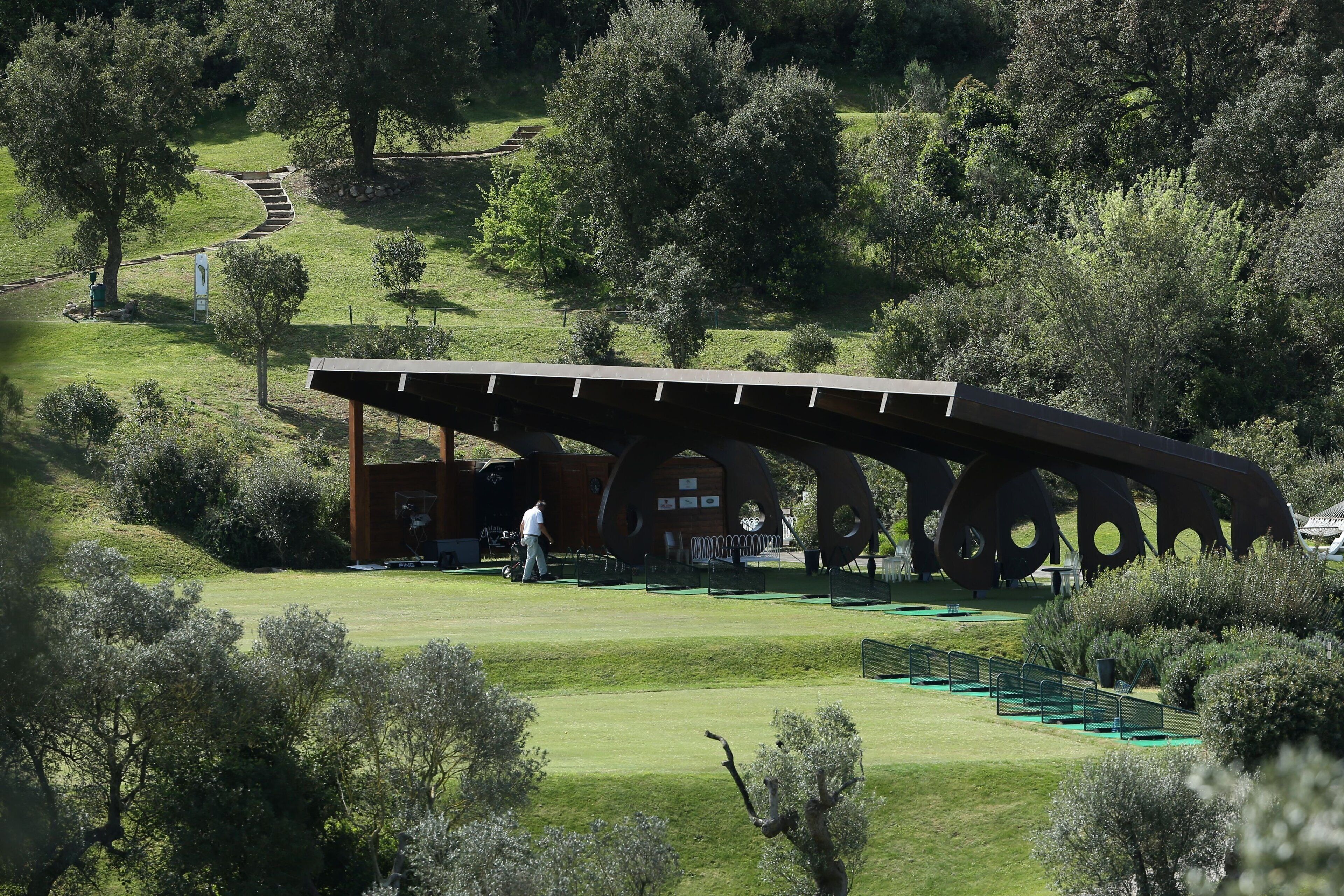 A modern building with a unique architectural design, surrounded by lush greenery and a well-maintained lawn.