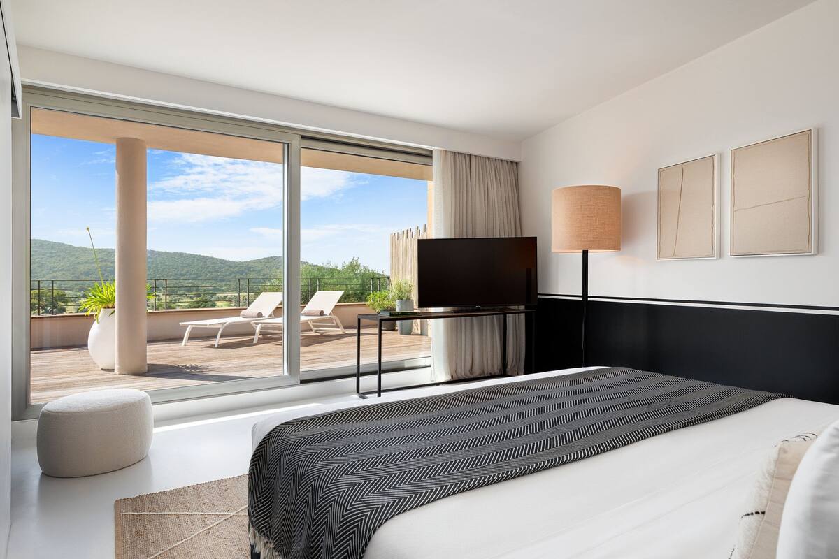 Een moderne hotelkamer met een groot bed, een flatscreen televisie, een nachtkastje en uitzicht op de omgeving.