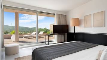 A modern hotel room with a large bed, a flat-screen TV, a bedside table, and a view of the outdoors.