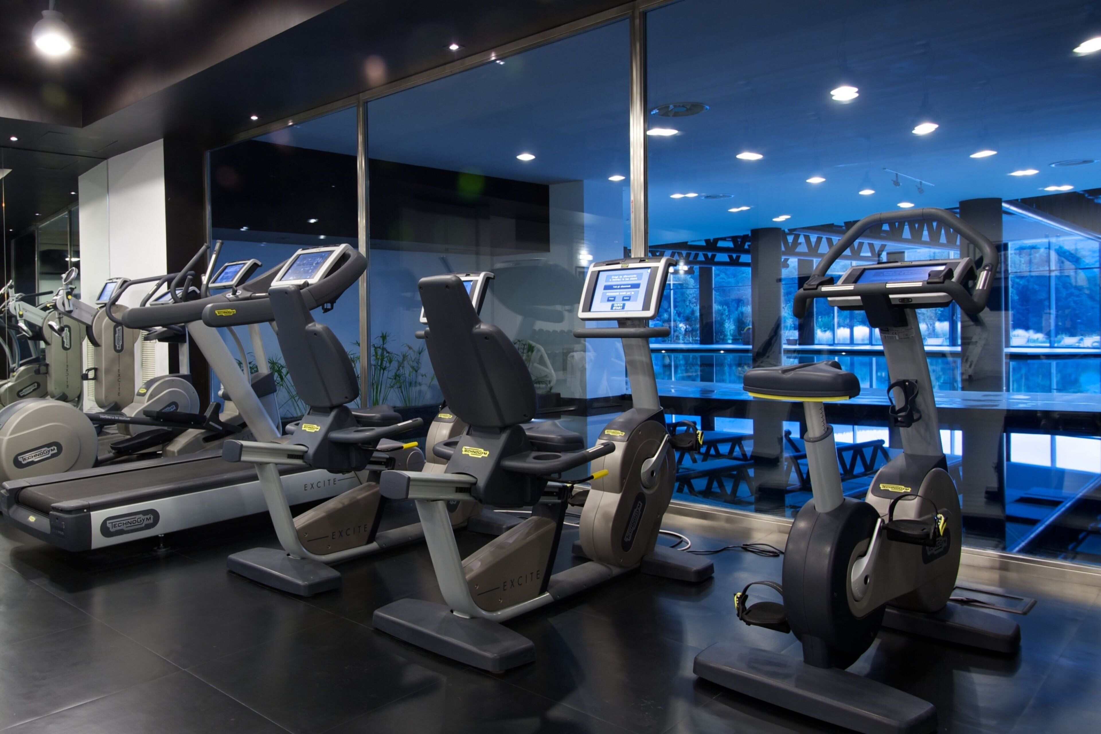 Ein Fitnessraum mit verschiedenen Cardiogeräten, darunter Laufbändern und Crosstrainern, die in einer Reihe angeordnet sind.
