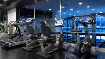 Ein Fitnessraum mit verschiedenen Cardiogeräten, darunter Laufbändern und Crosstrainern, die in einer Reihe angeordnet sind.