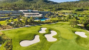 A golf course with bunkers, a swimming pool, and a hotel complex with multiple buildings.
