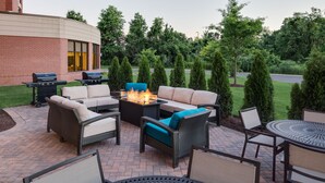 Une terrasse extérieure aménagée avec des meubles en osier, un foyer et un barbecue.