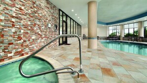Une piscine intérieure dotée d’un sol carrelé, d’un mur en briques et d’une cloison en verre.