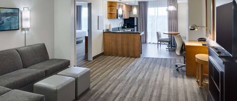 Una habitación de hotel moderna con sala de estar, kitchenette y comedor.