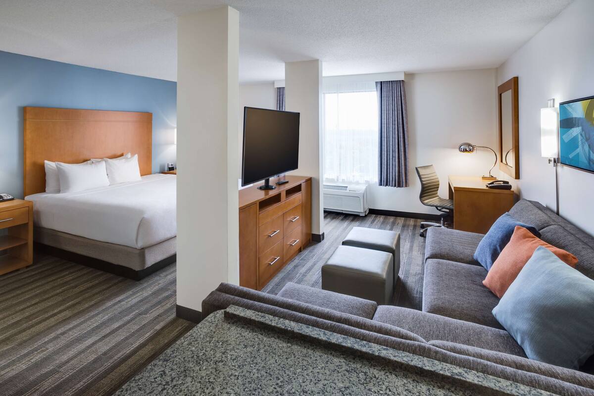 Una habitación de hotel con una cama, televisión, sofá, escritorio y una silla.