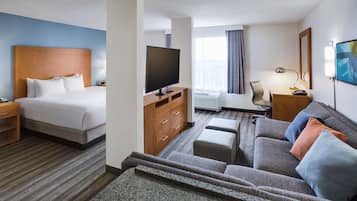 A hotel room with a bed, a TV, a sofa, a desk, and a chair.