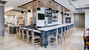 Une cuisine moderne dotée d’un îlot central, de tabourets de bar et de luminaires suspendus.