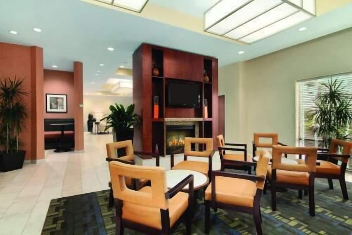 Un vestíbulo de hotel con chimenea, zona de estar y televisor montado en un mueble de madera.
