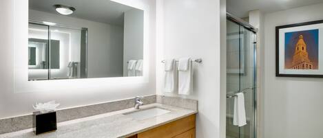 A modern bathroom with a large mirror, a sink, and a glass shower enclosure.