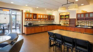 A modern kitchen with wooden cabinets, a large island, and bar stools. - Hyatt Place Lake Mary/Orlando North (Lake Mary)