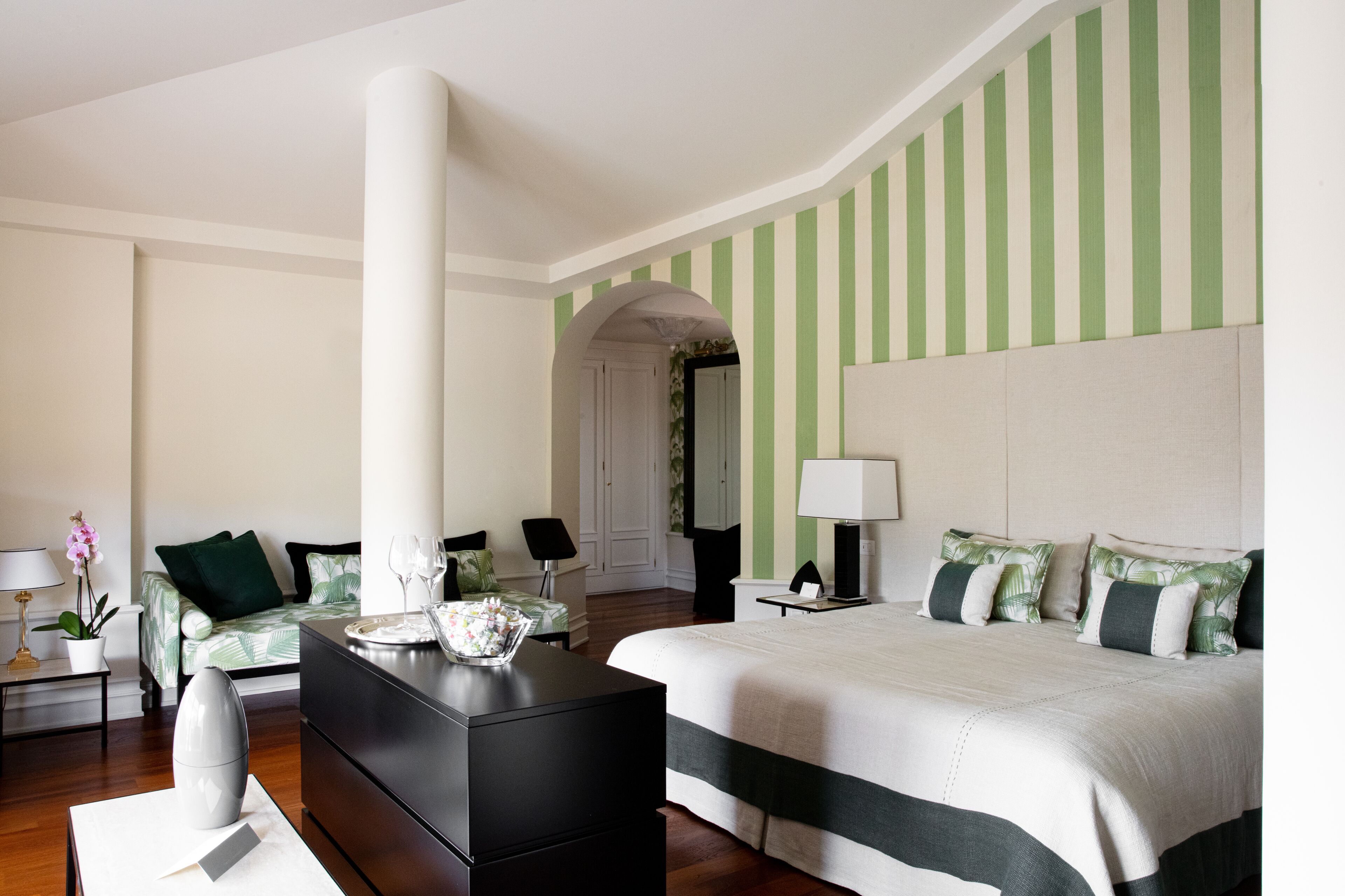A hotel room with a large bed, a desk, a chair, and a nightstand.