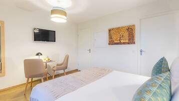Ein Schlafzimmer mit einem Bett, einem Schreibtisch, zwei Stühlen, einem Fernseher und Bildern an der Wand.