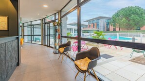 A spacious indoor area with large windows, modern chairs, and a view of the outside. - Appart’City Confort Toulouse Purpan (Toulouse)