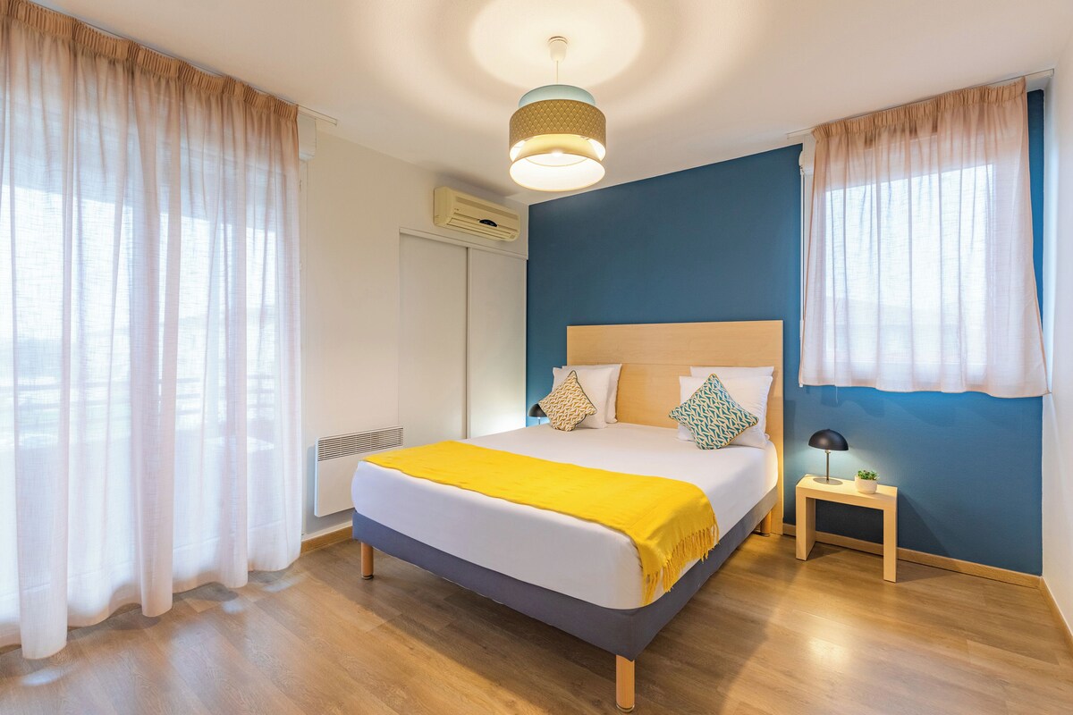 A bedroom with a bed, bedside table, and curtains.