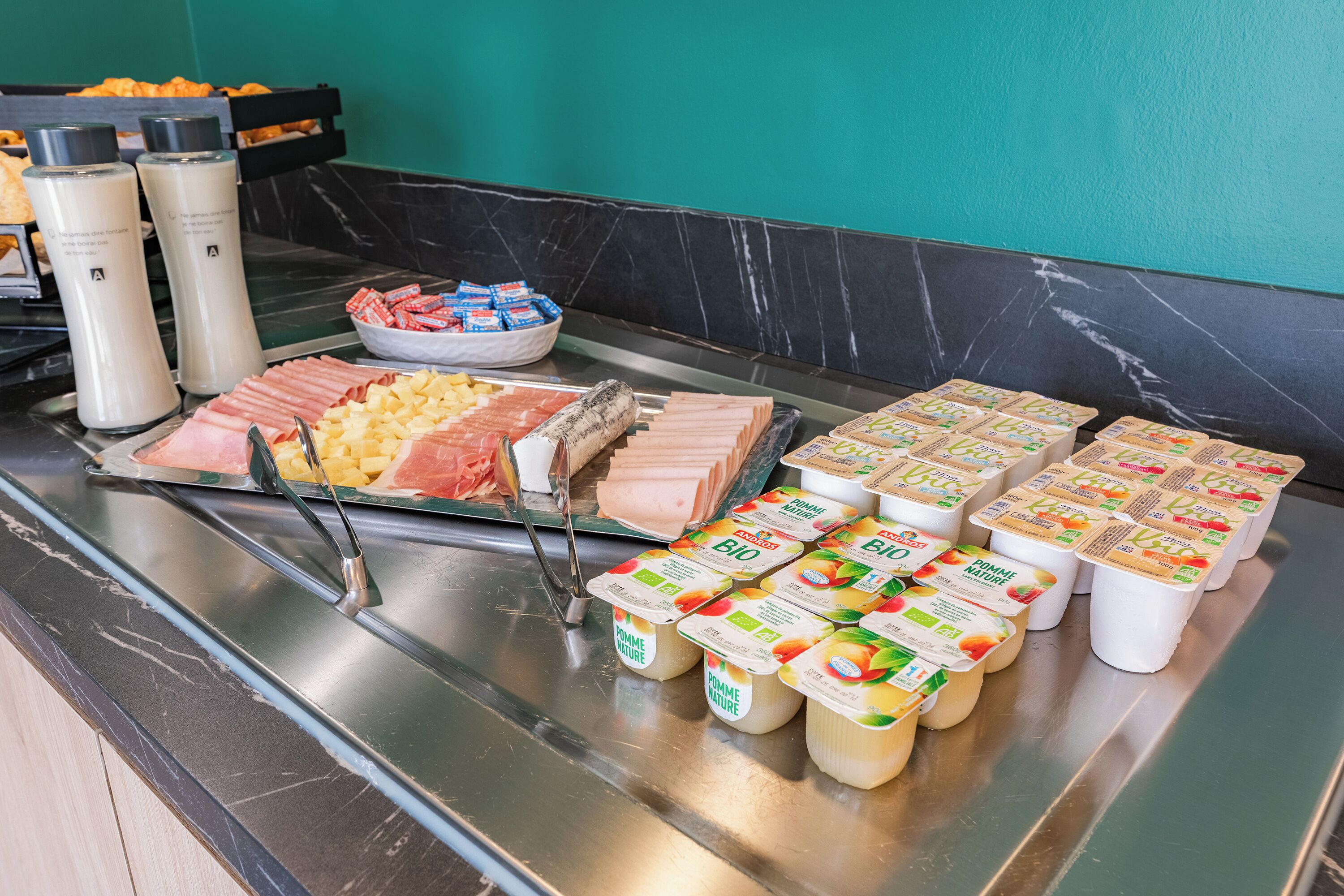 A buffet with various food items including meats, cheeses, and yogurt.
