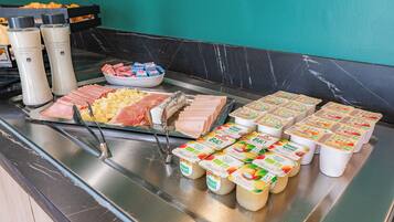 A buffet with various food items including meats, cheeses, and yogurt.