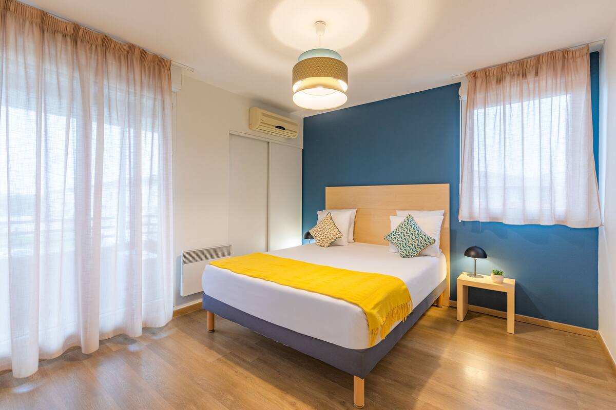 A bedroom with a bed, bedside table, and curtains.