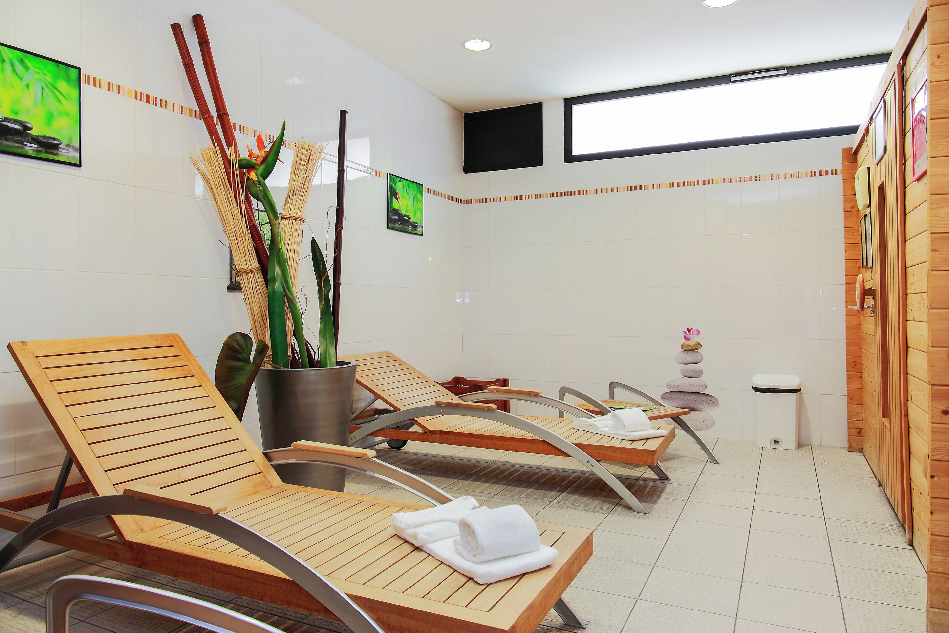 A spa area with wooden loungers, a potted plant, and a small stack of stones.