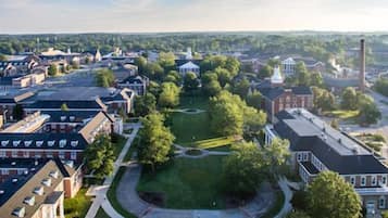 An aerial view of a town with a central green space, buildings, and a prominent church.