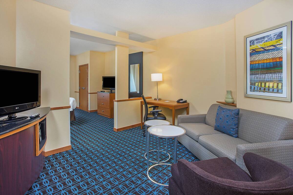Una habitación de hotel con televisión, sofá, escritorio y silla.