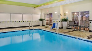 A swimming pool with a slide, a seating area with chairs, and a door leading to a room. - Fairfield Inn & Suites Cookeville (Cookeville)
