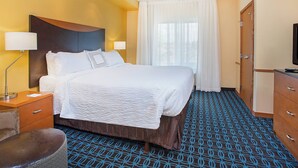 A hotel room with a large bed, a desk with a lamp, a chair, and a wardrobe. - Fairfield Inn & Suites Cookeville (Cookeville)