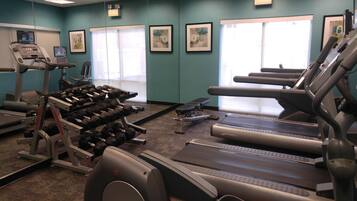 A gym with treadmills, dumbbells, and exercise equipment.