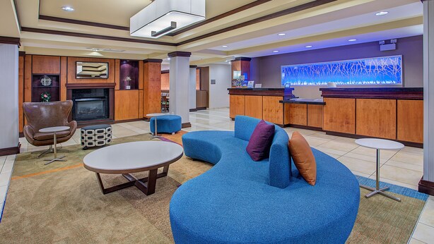 Un hall d’entrée moderne avec un canapé bleu, une cheminée, un comptoir d’accueil et un coin bar.
