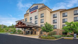 Un hôtel Fairfield Inn & Suites de la chaîne Marriott, doté d’une entrée abritée, d’une façade en pierre et d’un aménagement paysager soigné.