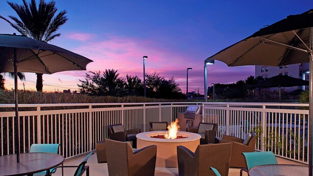 An outdoor patio area with a fire pit, wicker furniture, and umbrellas. - Residence Inn by Marriott Clearwater Downtown (Clearwater)