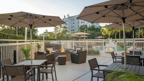 An outdoor patio area with tables and chairs, umbrellas, and a fire pit. - Residence Inn by Marriott Clearwater Downtown (Clearwater)