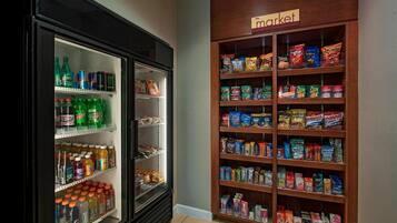 A vending machine and a snack shelf in a room.