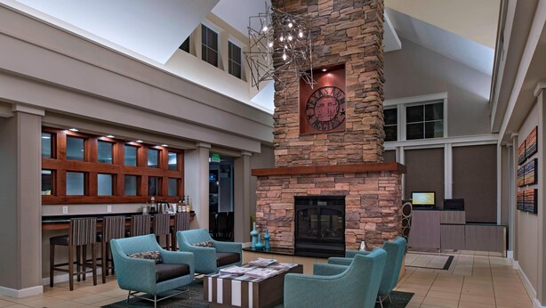 A spacious lobby with a high ceiling, a stone fireplace, and a bar area with stools. - Residence Inn Bryan College Station (College Station)