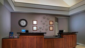 A reception desk with a clock, framed pictures, and a computer. - Residence Inn Bryan College Station (College Station)