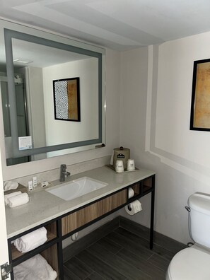 Une salle de bain moderne avec un grand miroir, un lavabo, des toilettes et un porte-serviettes.