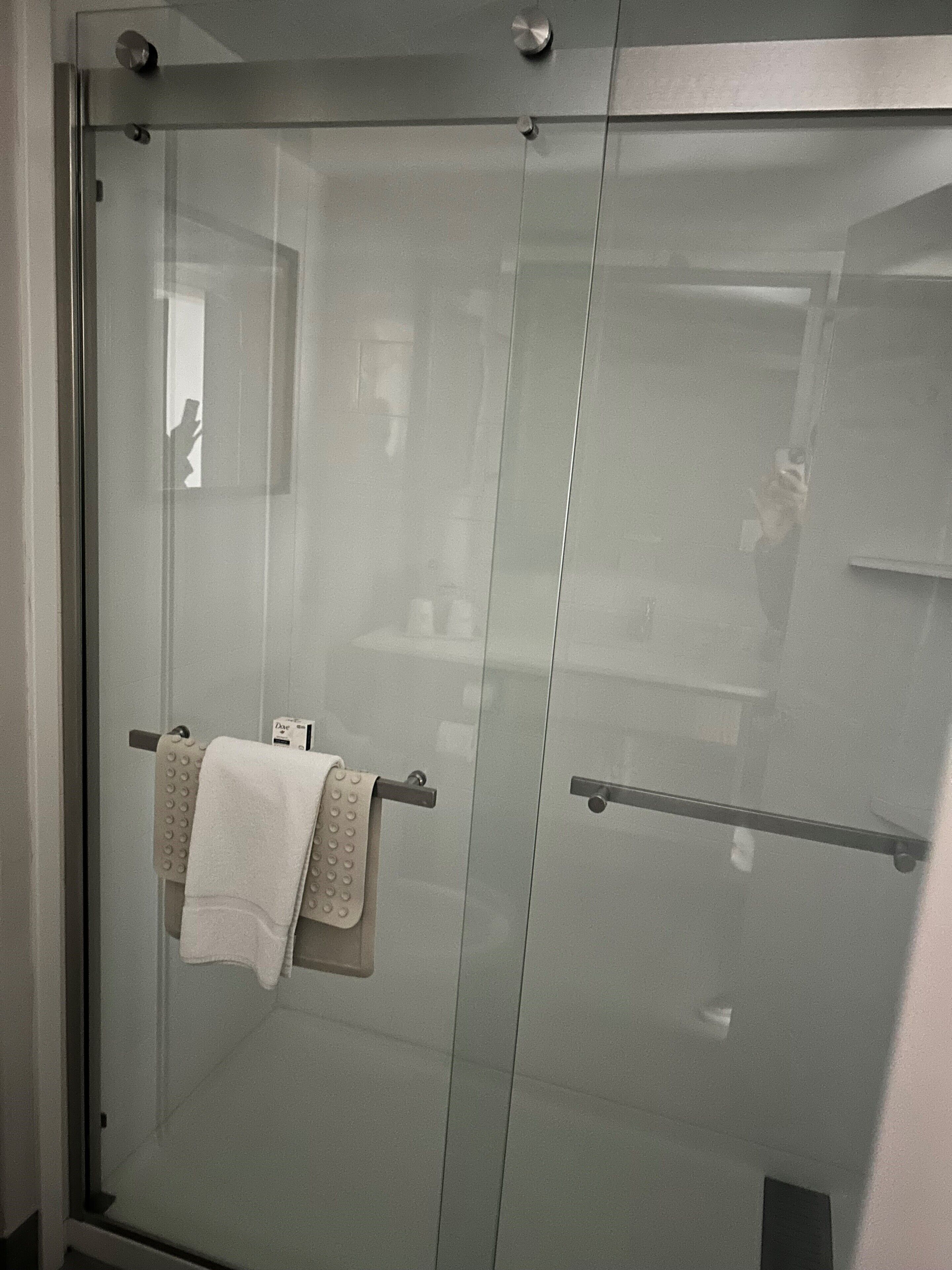 A glass shower enclosure with a towel rack holding a white towel.