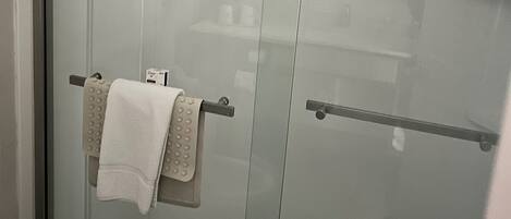 A glass shower enclosure with a towel rack holding a white towel.