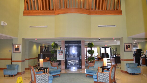 A spacious lobby with a high ceiling, a central fireplace, and seating areas. - Wingate by Wyndham Richmond Short Pump (Richmond)