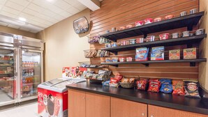 A self-service food area with refrigerated cases, shelves stocked with canned goods, and a variety of packaged snacks. - Wingate by Wyndham Richmond Short Pump (Richmond)